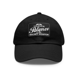 May include: Black baseball cap with a white patch that reads "TRADER Patience is the SECRET WEAPON".