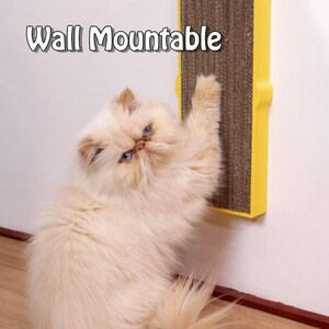 May include: A fluffy, cream-colored cat with blue eyes interacts with a wall-mounted cat scratcher. The scratcher is yellow with a brown, corrugated scratching surface. Text on the image reads "Wall Mountable".