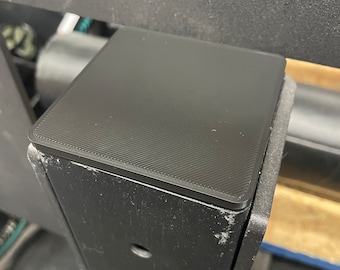 May include: Black square-shaped plastic cap for a metal post. The cap has a textured surface and is designed to protect the post from damage.