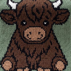 May include: A square knitted blanket featuring a central graphic of a brown highland cow with white horns, dark brown accents, and a light brown muzzle. The background is a solid sage green color, and the entire piece is crafted with thick yarn.