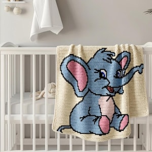 Könnte beinhalten: Eine cremefarbene Babydecke aus Häkelarbeit mit einem blauen Elefanten-Design. Der Elefant hat rosa Ohren und sitzt auf der Decke, die über ein weißes Kinderbett drapiert ist. Die Decke hat ein pixeliges Design und scheint handgefertigt zu sein.
