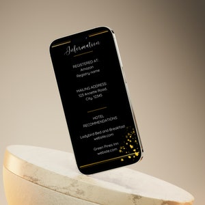 May include: A black smartphone with a gold border displays information about a wedding. The text includes the words "Information", "Registered At", "Amazon", "Registry name", "Mailing Address", "Hotel Recommendations", "Ladybird Bed and Breakfast", "website.com", "Green Pines Inn", and "webiste.com".