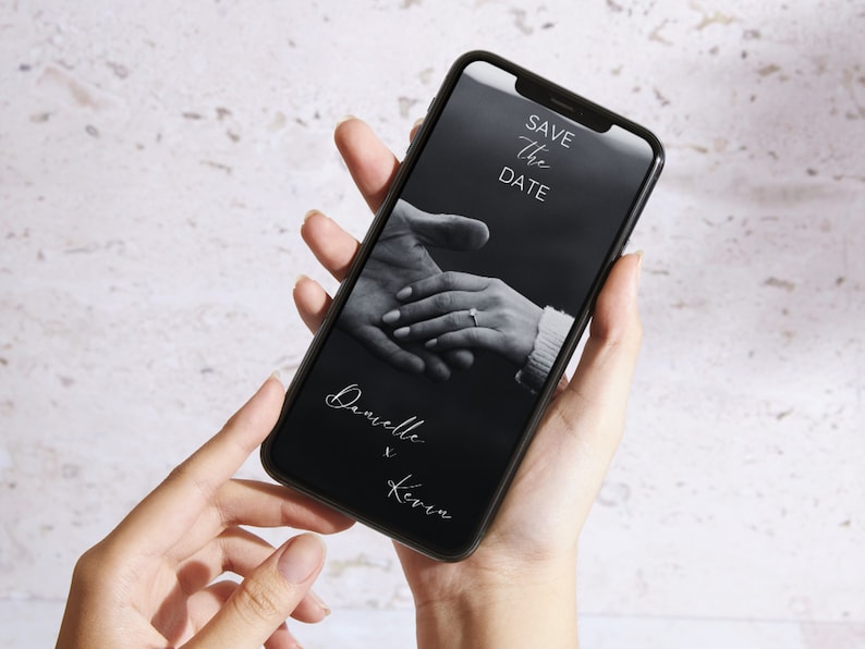 Puede incluir: Una foto en blanco y negro en la pantalla de un tel&eacute;fono inteligente muestra dos manos entrelazadas con un anillo en un dedo. El texto "Save the Date" est&aacute; en la parte superior de la pantalla y el texto "Danielle & Kevin" est&aacute; en la parte inferior de la pantalla.