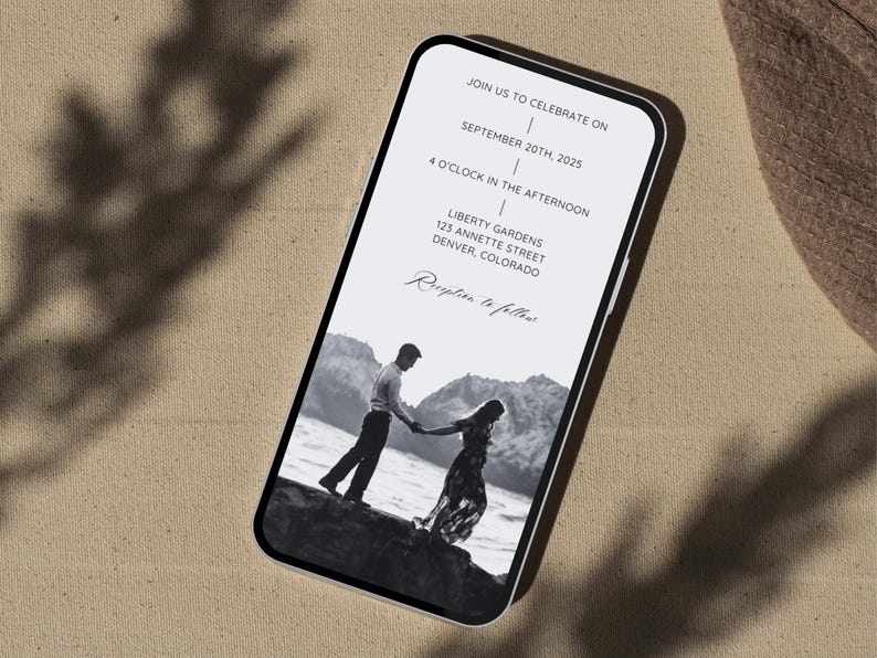 May include: A black and white photo of a couple holding hands on a beach. The invitation is for a wedding reception on September 20th, 2025 at 4:00 PM at Liberty Gardens, 123 Annette Street, Denver, Colorado. Reception to follow.
