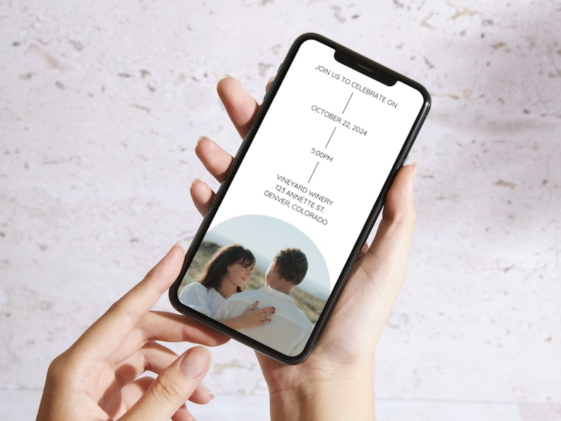May include: A mobile phone screen displaying a wedding invitation. The invitation is for a wedding on October 22, 2024, at 5:00 PM at Vineyard Winery in Denver, Colorado. A photo of a couple is in the background.