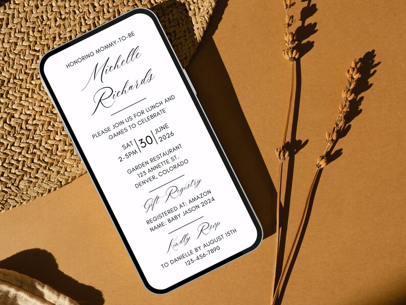 May include: A white and black mobile phone screen displaying a baby shower invitation for Michelle Richards. The invitation includes the date, time, location, and gift registry information. The text reads "Honoring Mommy-to-be Michelle Richards. Please join us for lunch and games to celebrate Sat | 30 | June 2-5pm | 2026 Garden Restaurant 123 Annette St. Denver, Colorado Gift Registry Registered at: Amazon Name: Baby Jason 2024 Kindly RSVP To Danielle by August 15th 123-456-7890"