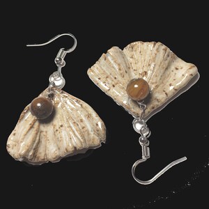 May include: A pair of earrings featuring a white ceramic ginkgo leaf design with a brown tiger's eye stone accent.