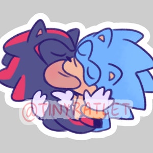 May include: A sticker featuring a cartoon drawing of two characters, Sonic the Hedgehog and Shadow the Hedgehog, kissing. Sonic is blue with a white and blue quiff, and Shadow is black with red highlights and a red quiff. The characters are drawn in a cute, cartoon style.