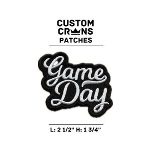 May include: Black embroidered patch with the words "Game Day" in white script. The patch is 2 1/2 inches long and 1 3/4 inches high. The text "CUSTOM CRANS PATCHES" is above the patch.