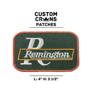 May include: A green and white embroidered patch with the text "Remington" in a yellow banner. The patch is 4 inches wide and 2 1/2 inches tall.
