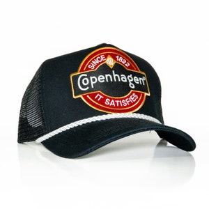 May include: Black trucker hat with a red, white, and gold embroidered patch that says "Since 1822 Copenhagen It Satisfies".