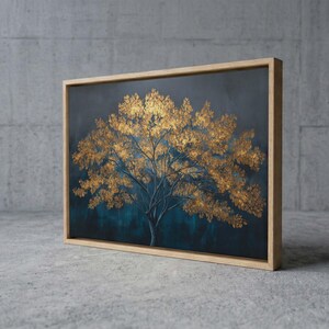 May include: A framed canvas art piece featuring a stylized tree with gold-colored leaves against a dark teal background. The tree's trunk and branches are a darker shade, and the frame is made of light-colored wood. The artwork is displayed on a concrete surface.