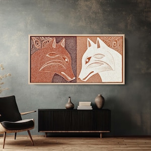May include: A framed artwork featuring two stylized fox profiles. One fox is rendered in shades of brown, the other in white, set against a textured background. The artwork is displayed above a black cabinet.