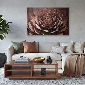 May include: A living room scene featuring a large, abstract floral canvas in shades of brown above a cream-colored sectional sofa. Decorative pillows in various textures and colors, a wooden coffee table, and a potted plant complete the cozy, modern aesthetic.
