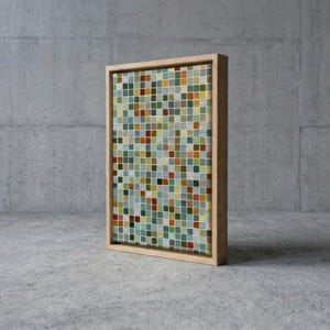 May include: A rectangular wall art piece featuring a grid of small, multicolored square tiles in shades of green, blue, yellow, orange, and white. The artwork is encased in a light-colored wooden frame, presenting a mosaic-like pattern.