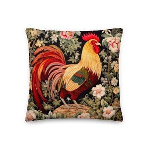 May include: A colorful pillow featuring a rooster with red, yellow, and green plumage standing in a garden with pink and white flowers on a black background.