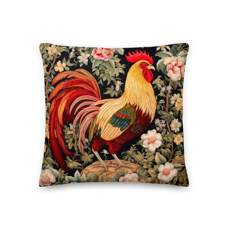 May include: A colorful pillow featuring a rooster with red, yellow, and green plumage standing in a garden with pink and white flowers on a black background.