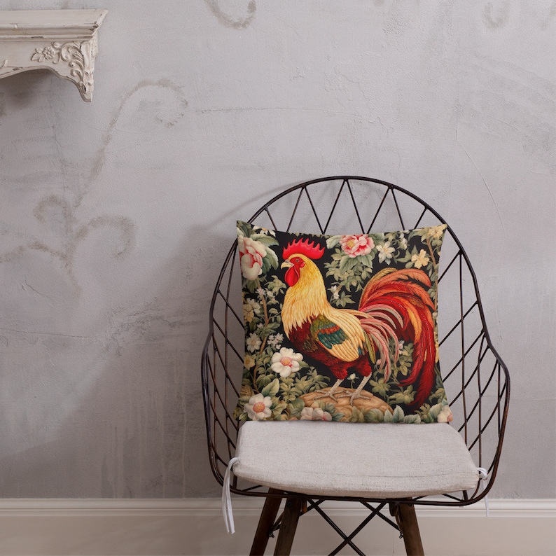 May include: A throw pillow with a colorful rooster design on a black background. The rooster is surrounded by flowers and leaves. The pillow is sitting on a chair.