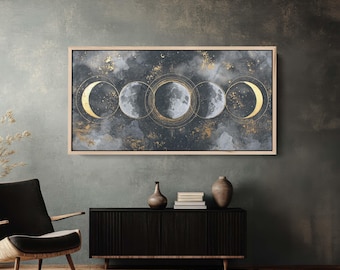 May include: A framed canvas art piece depicting the phases of the moon. The artwork features a dark, cloudy background with gold accents and circular outlines. The moon phases are rendered in shades of gray and gold.