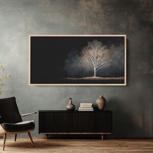 May include: A framed art print featuring a solitary tree with white branches against a dark background. The artwork is displayed above a black cabinet with decorative items, including a vase and books. The room has a modern aesthetic.