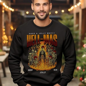 以下が含まれることがあります： 炎の中にいる骸骨のグラフィックと「Have a Jolly Merry Hell-Mas Merry Jolly Dead」というテキストが書かれた黒いスウェットシャツ。