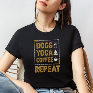 Könnte beinhalten: Ein schwarzes T-Shirt mit einer goldenen Grafik, auf der "Dogs, Yoga, Coffee, Repeat" steht, mit Symbolen für einen Hund, eine Person, die Yoga macht, und eine Tasse Kaffee.
