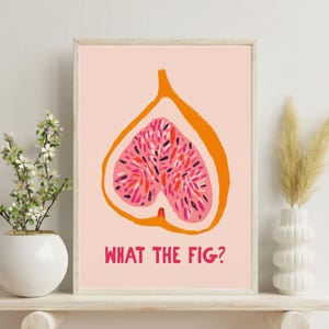 Pu&ograve; includere: Stampa artistica incorniciata con un fico tagliato a met&agrave;, arancione e rosa su sfondo rosa chiaro. Il testo "WHAT THE FIG?" &egrave; stampato in rosso sotto. La stampa &egrave; esposta su una mensola bianca. Design moderno e minimalista.