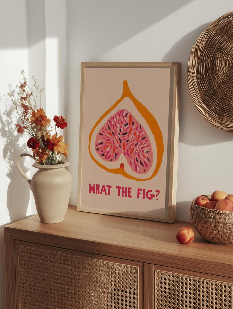 Pu&ograve; includere: Una stampa artistica incorniciata con un'illustrazione stilizzata di un fico tagliato, che mostra un interno rosa con semi colorati su sfondo pesca. La frase "WHAT THE FIG?" &egrave; stampata in rosa sotto.