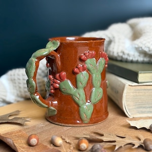 May include: A set of three ceramic mugs with a speckled, matte finish. Each mug features a different color: light blue, cream, and gray. The mugs have a simple, modern design, perfect for coffee or tea.