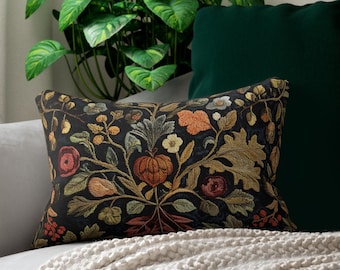 May include: A black and white throw pillow with a floral pattern. The pillow is on a white couch with a green throw blanket.