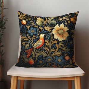 May include: A decorative cushion with a dark blue background featuring a stylised floral pattern in shades of gold, red, and blue. A small bird with orange and yellow plumage is perched on a branch in the centre of the design.