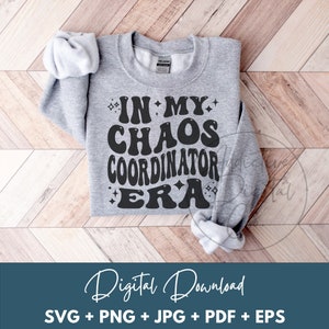 May include: A gray sweatshirt with the text "In My Chaos Coordinator Era" in black, stylized lettering. The text is surrounded by small stars.