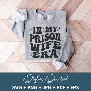 May include: A gray sweatshirt with the text "IN MY PRISON WIFE ERA" in black, stylized lettering with sparkling stars around the text.