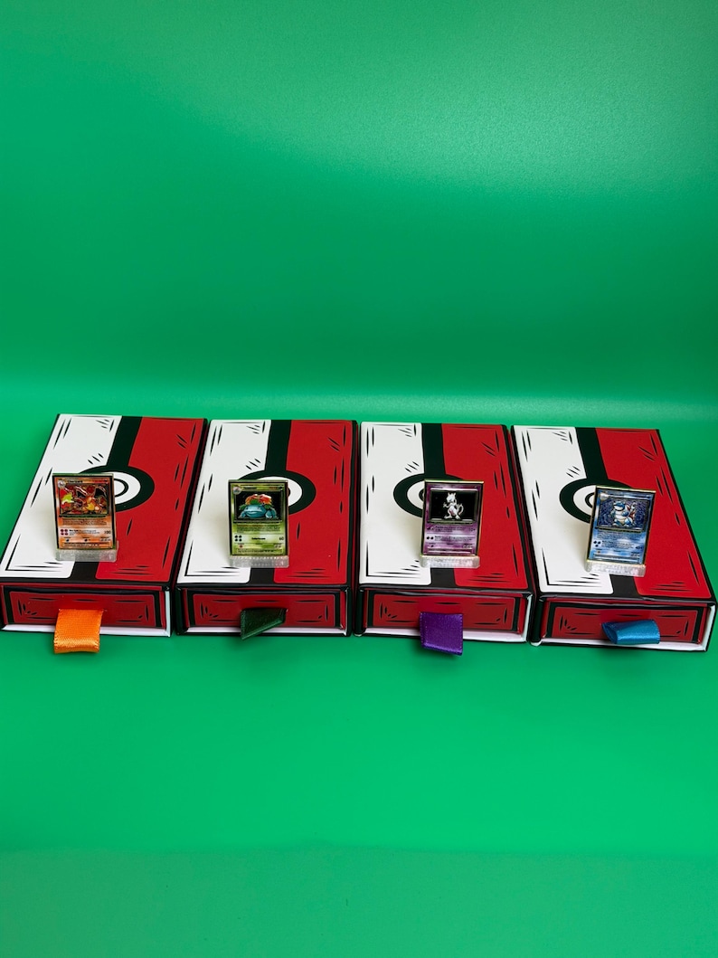 May include: Four red and white card storage boxes with black accents and colorful pull tabs. Each box holds a trading card in a clear stand. The background is a solid green.
