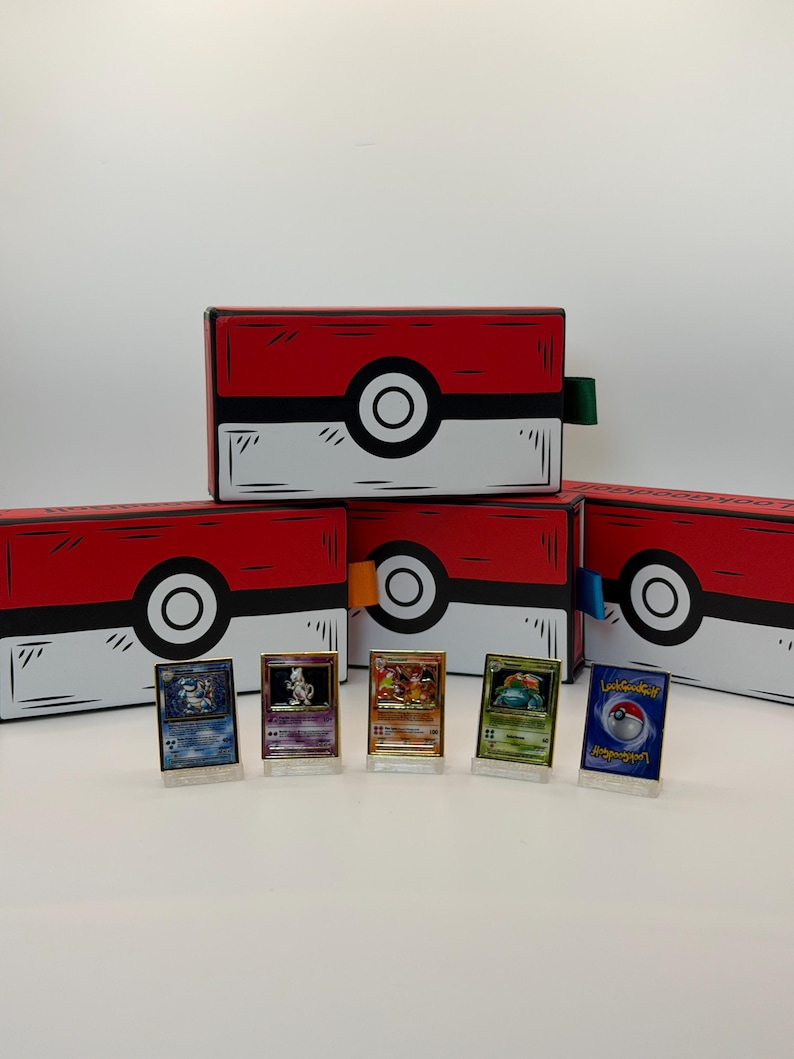 May include: Red and white boxes with black outlines and a large white circle with a black center. The boxes are arranged with several Pokemon trading cards in front. The cards are in clear stands.