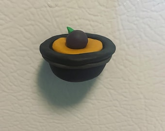 Ett enda plommon flyter i parfym serverad i en mans hatt magnet