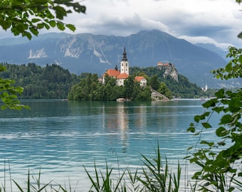 Lago Bled, Eslovenia, Lago Bled, Iglesia de la Asunción de María con el Castillo de Bled al fondo en un marco de hojas