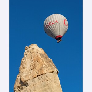 Hot air balloon with the print Turcia on it in the sky over the rock in Cappadocia, Turkey, Museum-Quality Matte Paper Poster