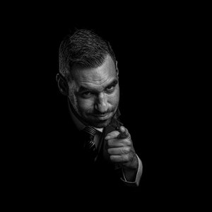 Man pointing finger, low key portrait, black background man, low key mans head, pointing gesture, dark mans portrait, black background man