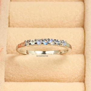Peut inclure: Une bague en argent avec sept pierres de lune claires serties en rangée.
