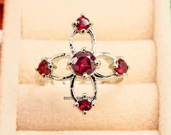 May include: A silver ring with a delicate, floral design featuring five red gemstones. The ring is set in a box with a light brown interior.