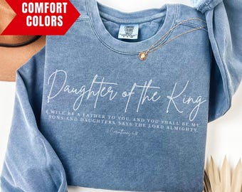 May include: A blue jean sweatshirt with the text "Daughter of the King" in white. The text is accompanied by a Bible verse: "I will be a father to you, and you shall be my sons and daughters says the Lord Almighty." (Malachi 2:10)