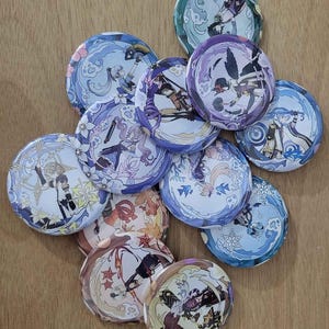 May include: A collection of 10 round, colorful buttons featuring anime characters. The buttons are decorated with swirling patterns and have a glossy finish.