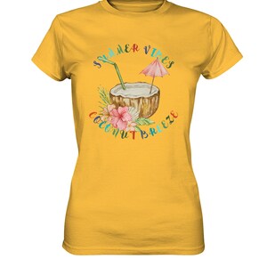 May include: A yellow t-shirt with a graphic of a coconut with a straw and a pink umbrella. The text "Summer Vibes Coconut Breeze" surrounds the coconut.