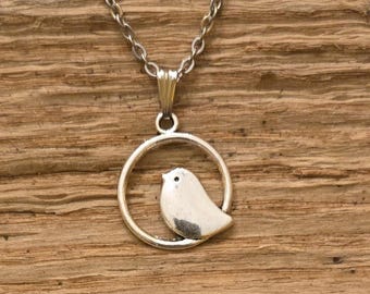 May include: A silver necklace with a pendant featuring a small bird inside a circle.