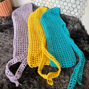 May include: Three crocheted headbands in different colors: lavender, yellow, and turquoise. The headbands are made with a simple crochet stitch and have a loose, flowy style.