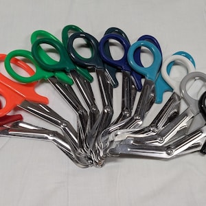 May include: A collection of medical shears with colorful handles. The handles are red, orange, green, dark green, blue, light blue, white, gray, and black. The blades are made of shiny metal.