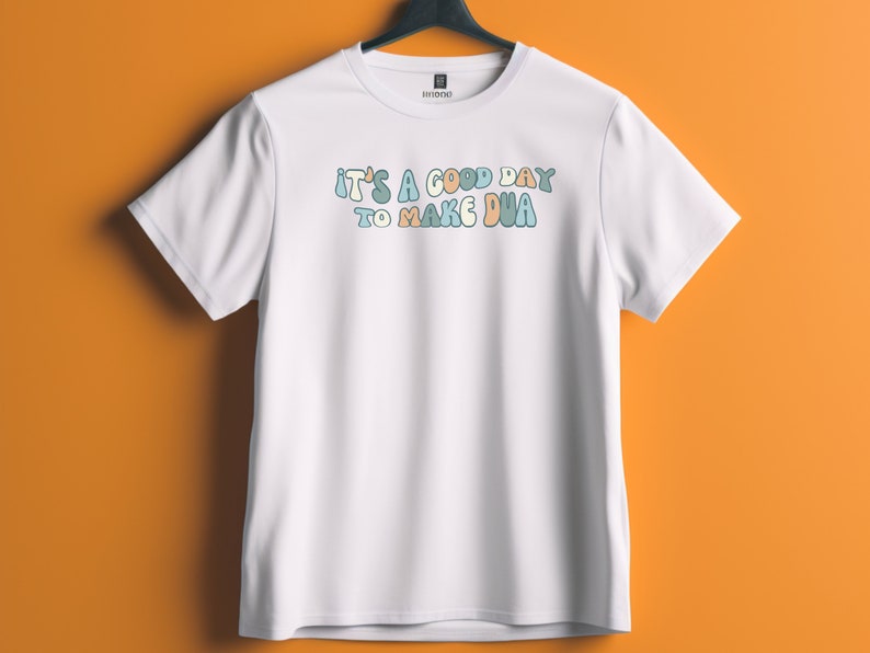 May include: White t-shirt with the text "It's a good day to make dua" in colourful, bubbly letters.