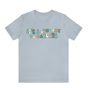 May include: Light blue t-shirt with the text "It's a good day to make dua" in a colourful, retro font.
