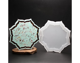 Può includere: Due stampi in silicone a forma di stella a otto punte. Uno stampo è riempito con resina verde menta chiaro con macchie marrone scuro e multicolori. Il secondo stampo è vuoto, bianco traslucido e mostra una superficie interna liscia.